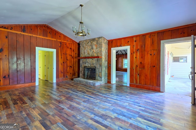 unfurnished living room with a stone fireplace, vaulted ceiling, dark hardwood / wood-style flooring, and wooden walls