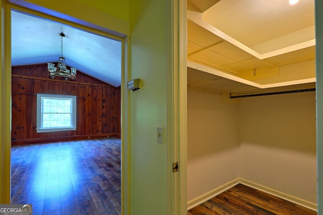 spacious closet featuring hardwood / wood-style floors, vaulted ceiling, and an inviting chandelier