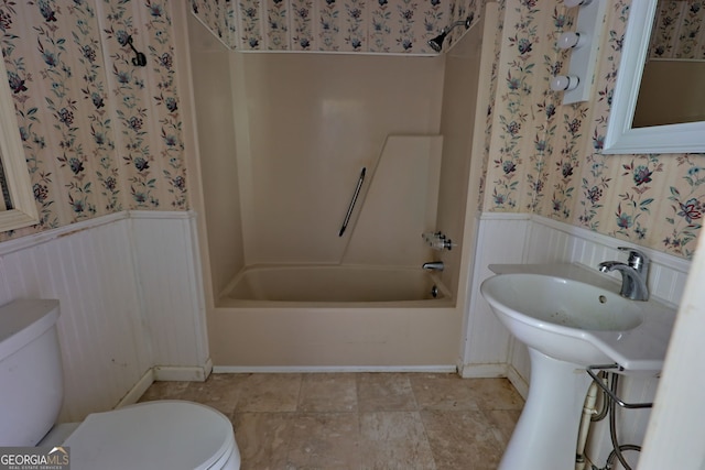 full bathroom featuring toilet, wainscoting, tub / shower combination, tile patterned floors, and wallpapered walls