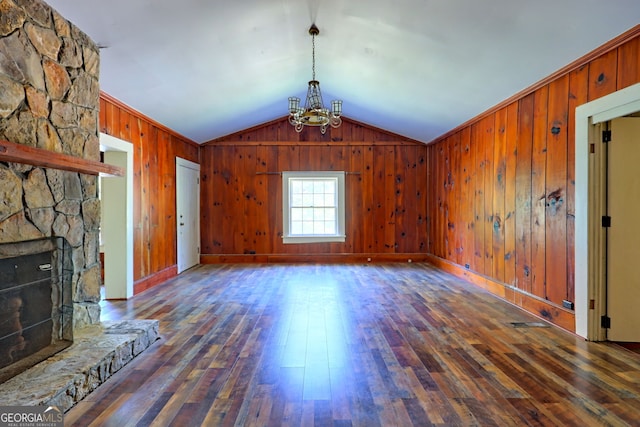 unfurnished living room featuring a fireplace, wooden walls, vaulted ceiling, and dark wood-type flooring