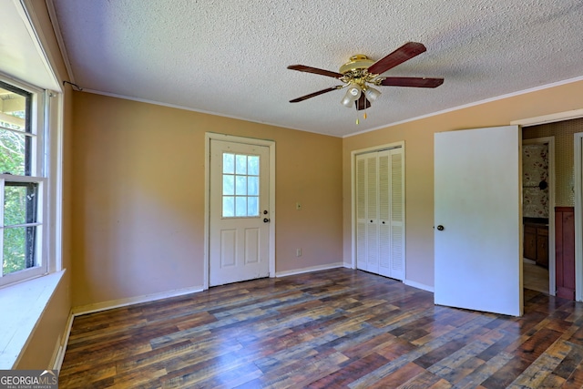 unfurnished bedroom featuring ceiling fan, a textured ceiling, dark hardwood / wood-style floors, and multiple windows