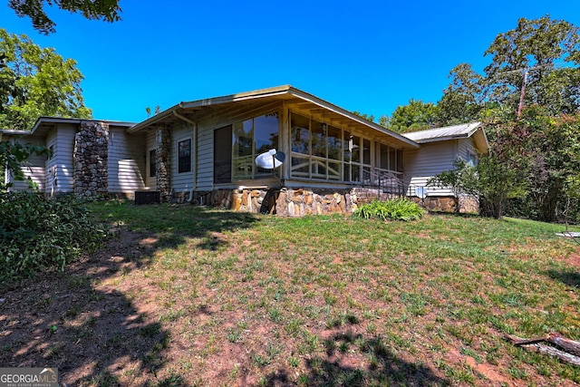 rear view of house with central AC unit and a yard