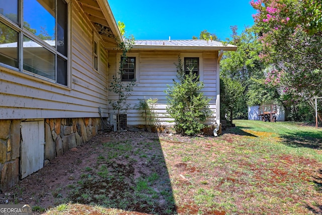 view of side of home featuring a yard, central AC, and metal roof