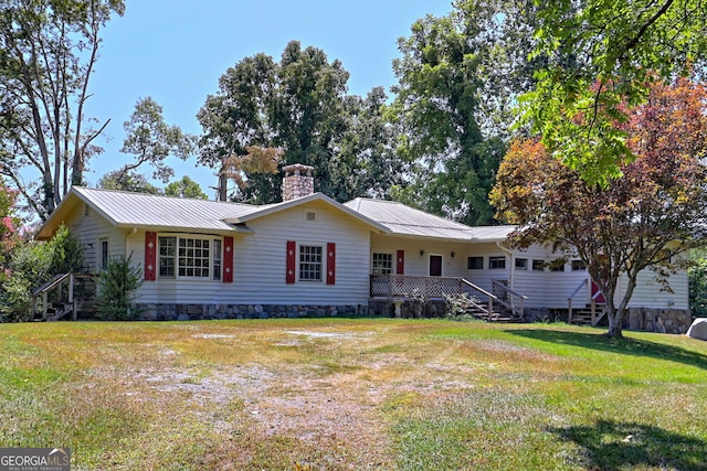 single story home with a chimney, metal roof, and a front yard