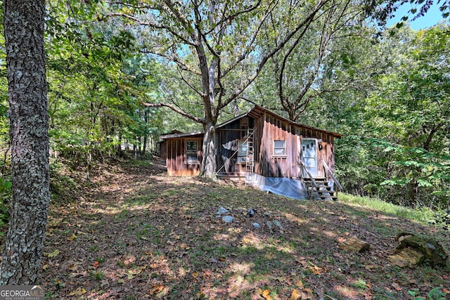 view of outbuilding with entry steps and a forest view