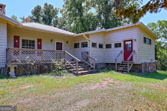 single story home with entry steps, metal roof, and a front lawn