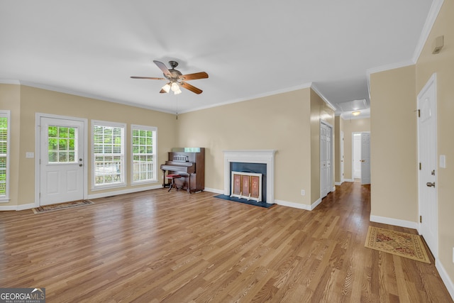 unfurnished living room featuring crown molding, a fireplace, light wood finished floors, ceiling fan, and baseboards