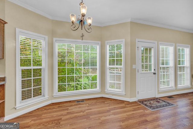 interior space with a healthy amount of sunlight, wood finished floors, visible vents, and crown molding