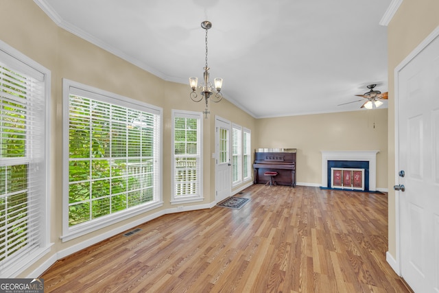 unfurnished living room with light hardwood / wood-style floors, crown molding, and ceiling fan with notable chandelier