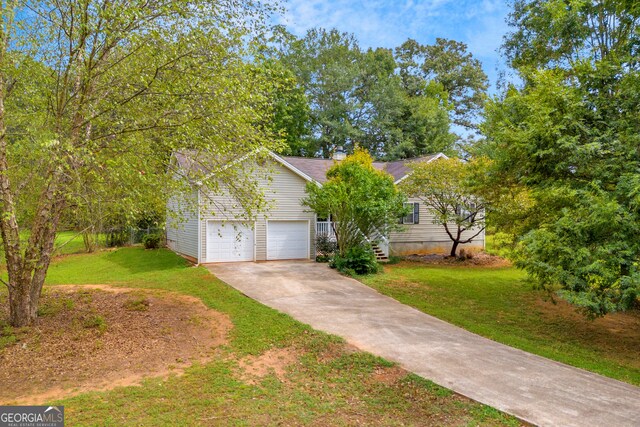 view of front of house with a garage, concrete driveway, and a front lawn