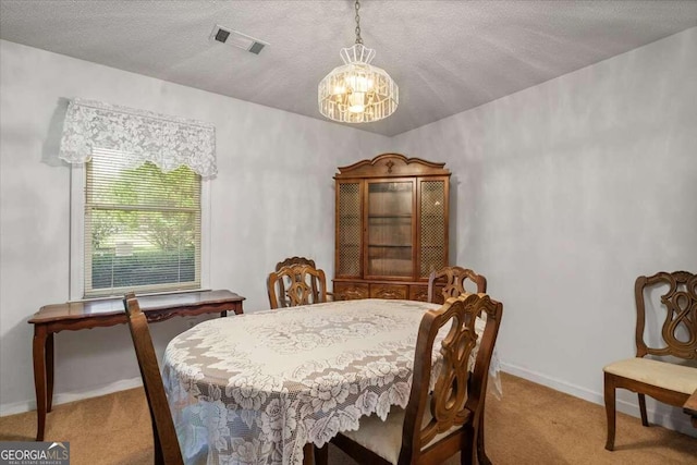 dining room with a textured ceiling, carpet flooring, and a chandelier