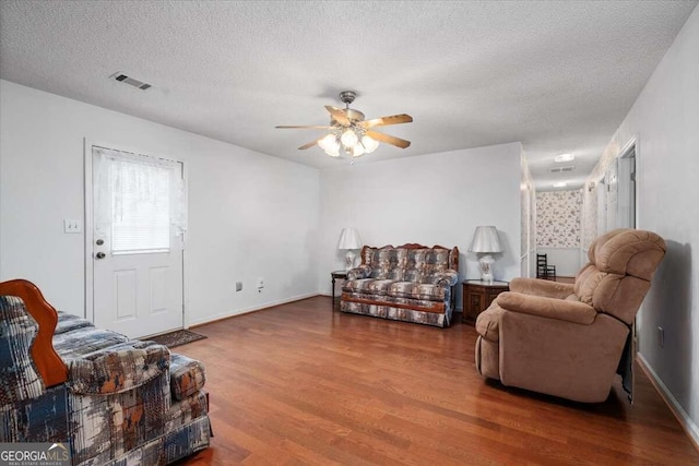 living room featuring ceiling fan, wood-type flooring, and a textured ceiling