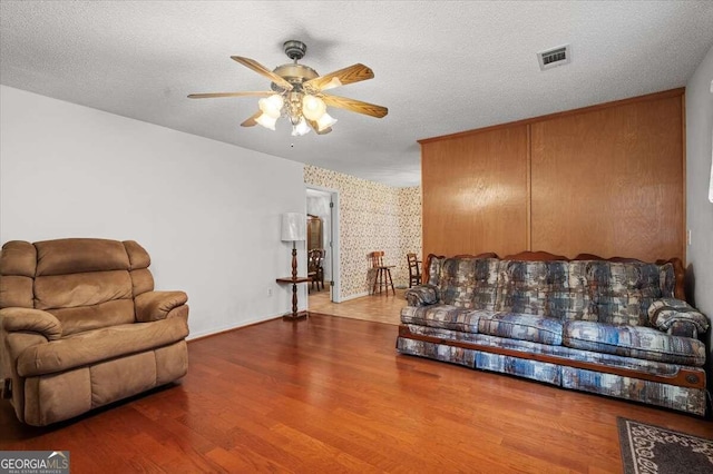 living room featuring a textured ceiling, ceiling fan, and hardwood / wood-style floors