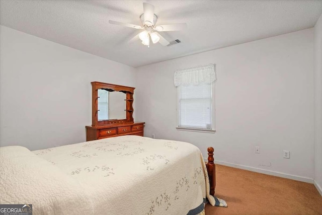 bedroom with ceiling fan, light carpet, and a textured ceiling