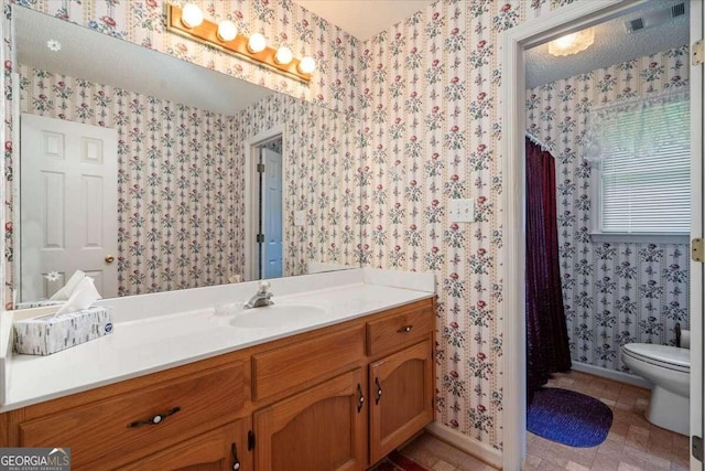 bathroom featuring tile patterned flooring, a textured ceiling, vanity, and toilet