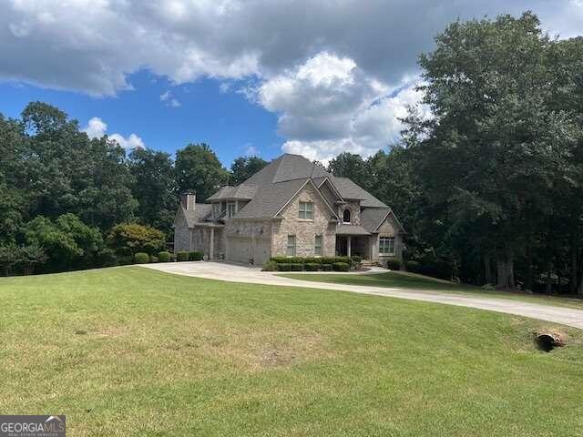 french country style house featuring a garage and a front yard