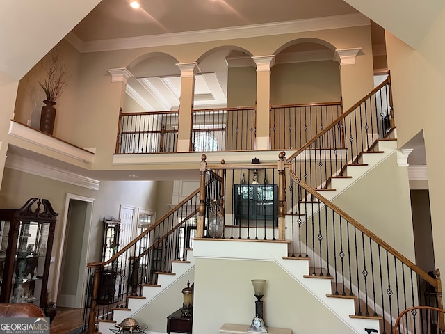 stairs featuring ornate columns, a towering ceiling, and ornamental molding