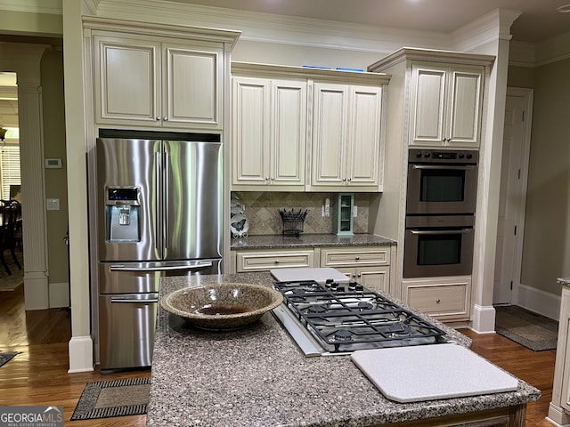 kitchen with decorative backsplash, dark wood-type flooring, cream cabinetry, and stainless steel appliances