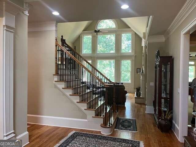 foyer entrance with ceiling fan, hardwood / wood-style floors, ornamental molding, and ornate columns