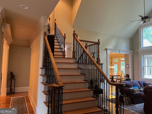 stairway featuring high vaulted ceiling, ceiling fan, and hardwood / wood-style floors