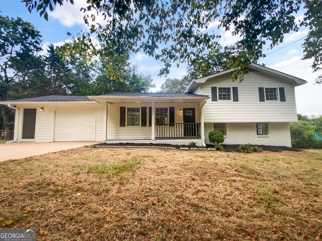 split level home with a garage, a front lawn, and covered porch