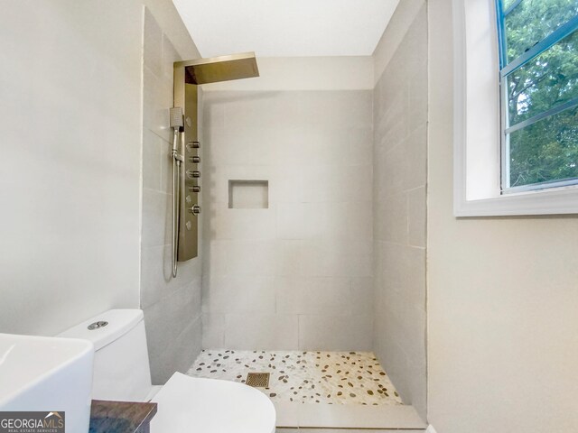 bathroom featuring tiled shower and toilet