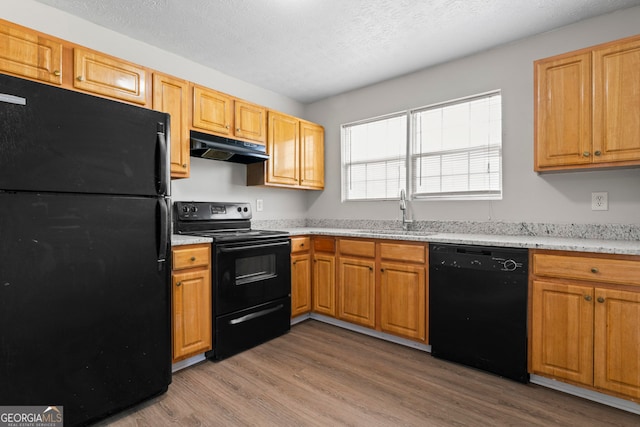 kitchen featuring a textured ceiling, black appliances, light hardwood / wood-style floors, and sink