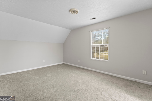 bonus room with a textured ceiling, lofted ceiling, and carpet flooring