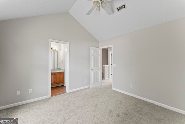 unfurnished bedroom featuring light carpet, ensuite bath, ceiling fan, and high vaulted ceiling