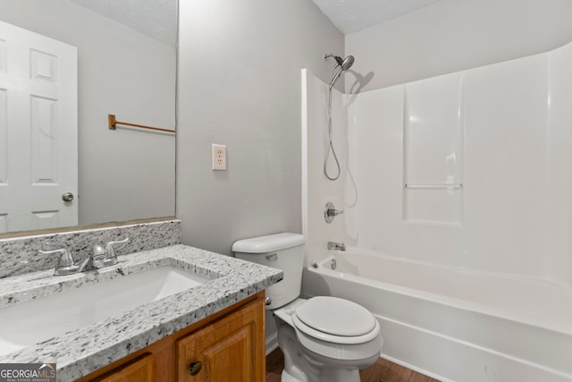 full bathroom featuring vanity, wood-type flooring, a textured ceiling, washtub / shower combination, and toilet