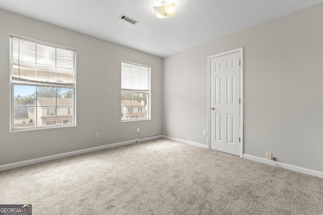 carpeted empty room featuring a textured ceiling