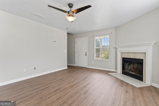 unfurnished living room featuring a textured ceiling, light hardwood / wood-style floors, a fireplace, and ceiling fan