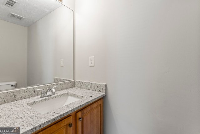 bathroom featuring vanity, toilet, and a textured ceiling