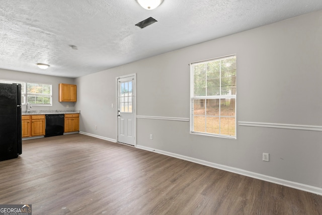 unfurnished living room featuring wood-type flooring, a textured ceiling, and sink