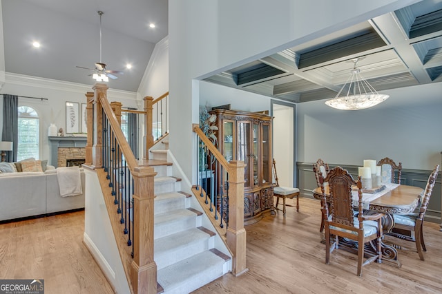 dining space with ceiling fan, light hardwood / wood-style floors, coffered ceiling, and a fireplace