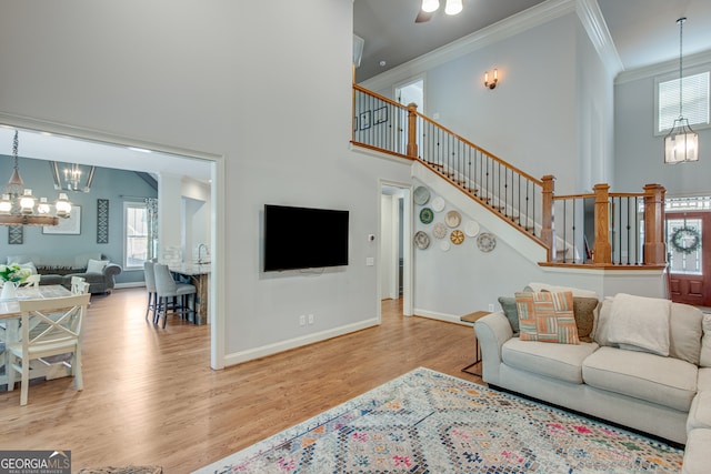 living room with a high ceiling, light hardwood / wood-style flooring, a chandelier, and ornamental molding