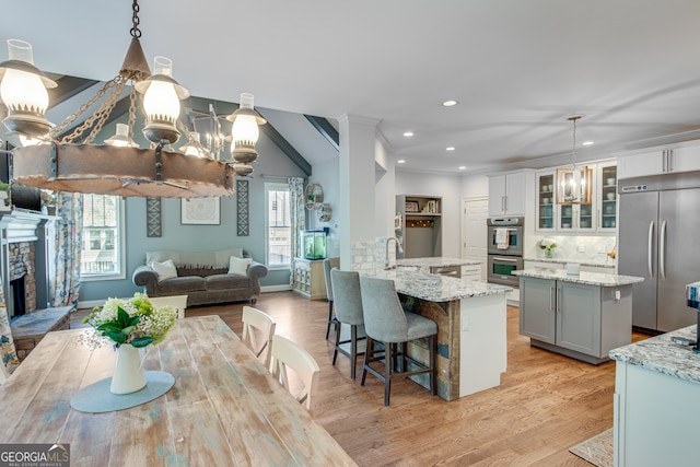 kitchen featuring light wood-type flooring, stainless steel appliances, pendant lighting, and a fireplace