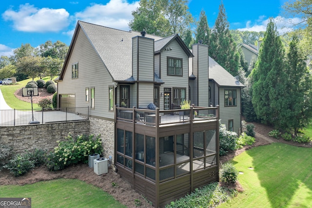 back of house with a garage, a sunroom, central AC, and a lawn