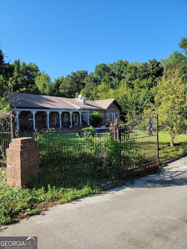 single story home with a fenced front yard, a gate, a front lawn, and brick siding