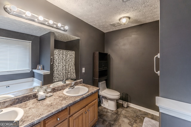 bathroom with a tub to relax in, tile patterned flooring, a textured ceiling, double vanity, and toilet