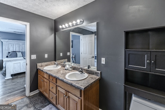 bathroom featuring dual vanity, wood-type flooring, and a textured ceiling