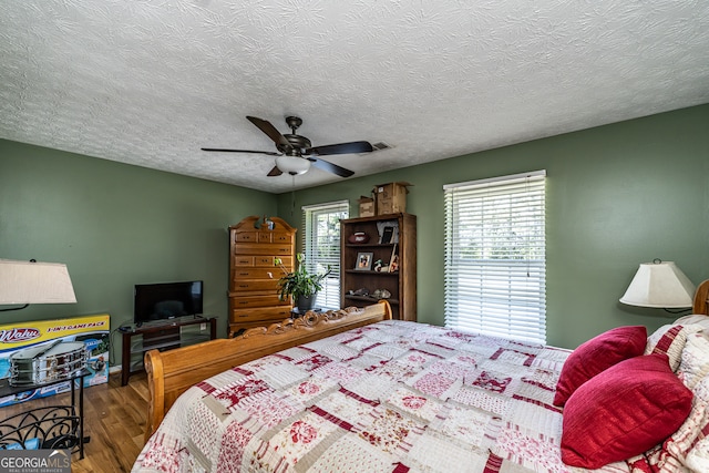 bedroom featuring ceiling fan, a textured ceiling, and wood-type flooring