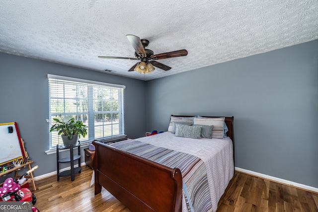 bedroom featuring hardwood / wood-style flooring, a textured ceiling, and ceiling fan