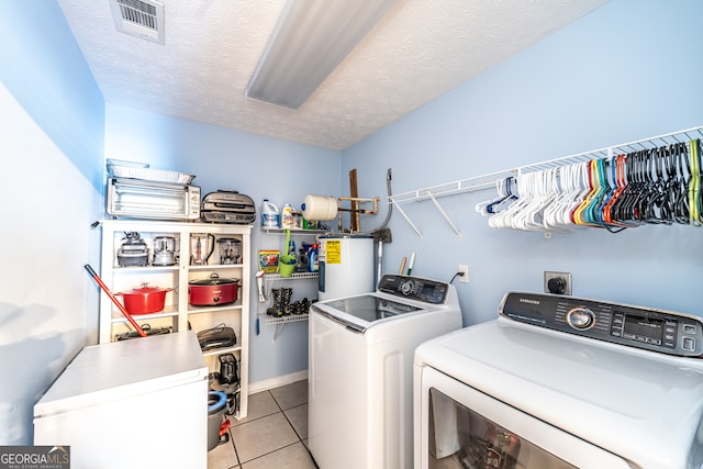 laundry room featuring light tile patterned flooring, independent washer and dryer, water heater, and a textured ceiling