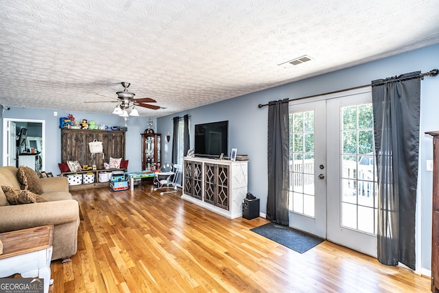 living room with ceiling fan, a textured ceiling, french doors, and wood-type flooring