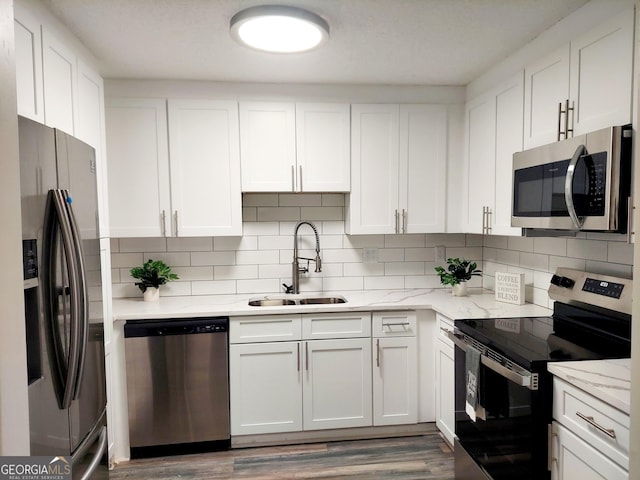 kitchen featuring light stone counters, sink, white cabinets, and stainless steel appliances