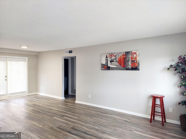 spare room with a textured ceiling and dark wood-type flooring