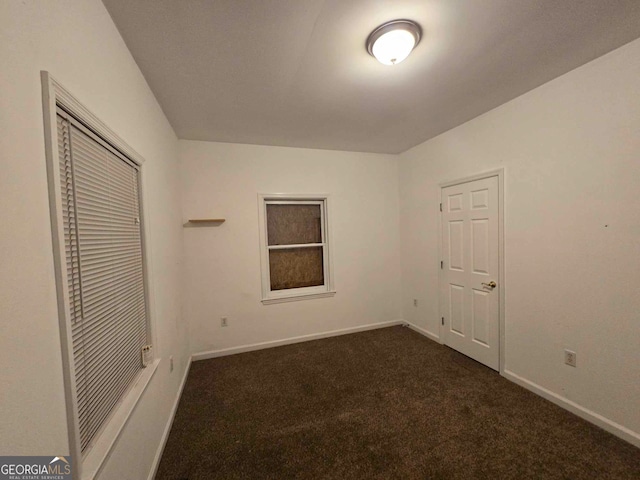 unfurnished bedroom with dark colored carpet and a closet