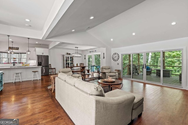 living room with vaulted ceiling, dark hardwood / wood-style flooring, a notable chandelier, and sink