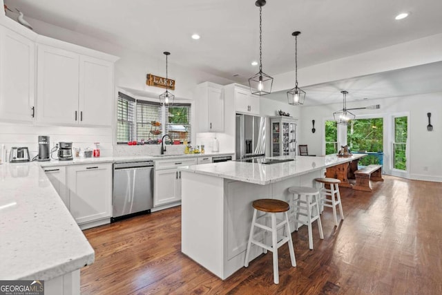 kitchen featuring appliances with stainless steel finishes, white cabinets, a center island, and pendant lighting